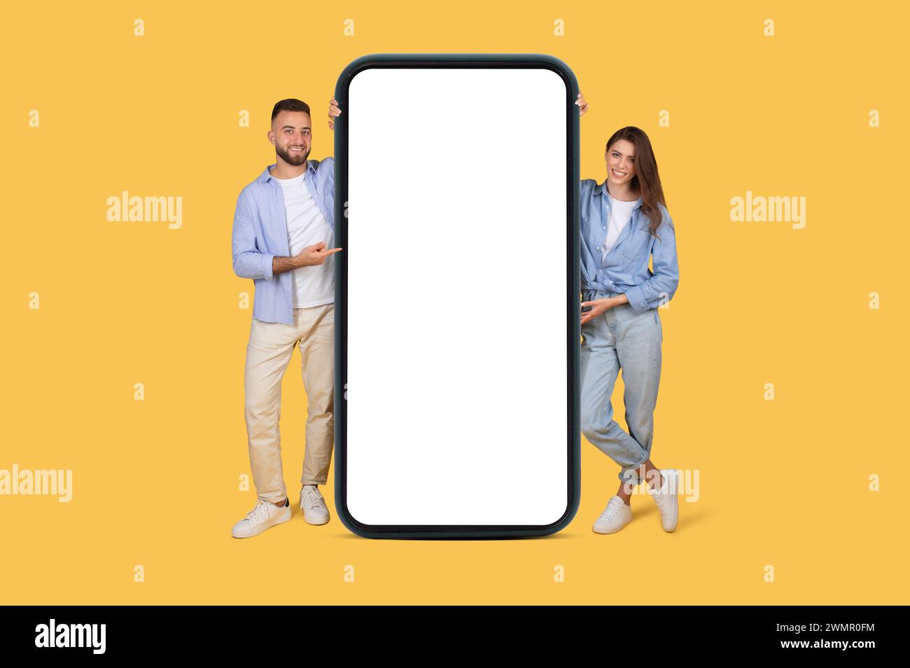 Couple joyeux présentant smartphone géant pour votre conception Banque D'Images