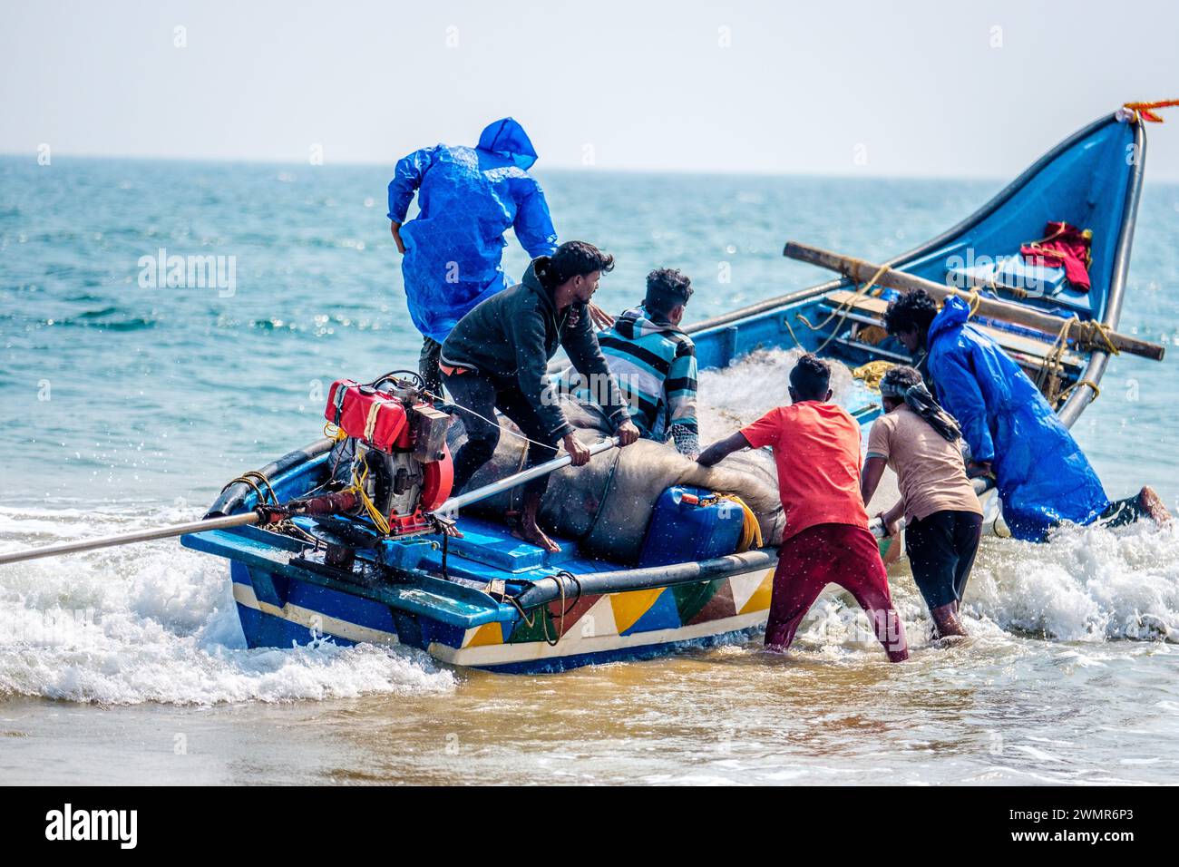 Pêcheurs lançant un bateau depuis une plage à Orissa / Odisha, Inde Banque D'Images