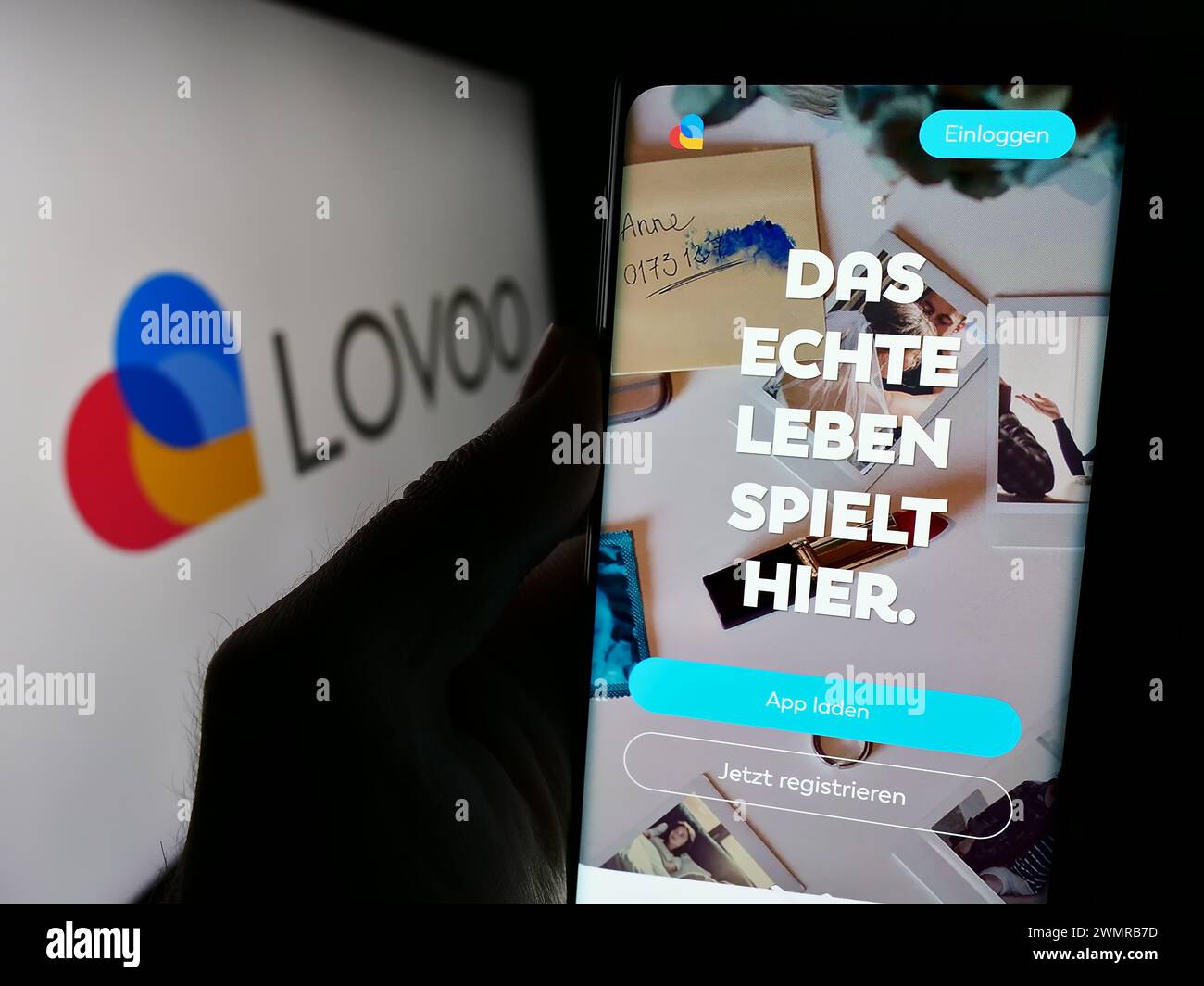 Personne tenant le téléphone portable avec la page Web de la société allemande de plate-forme de rencontre en ligne LOVOO devant le logo. Concentrez-vous sur le centre de l'écran du téléphone. Banque D'Images