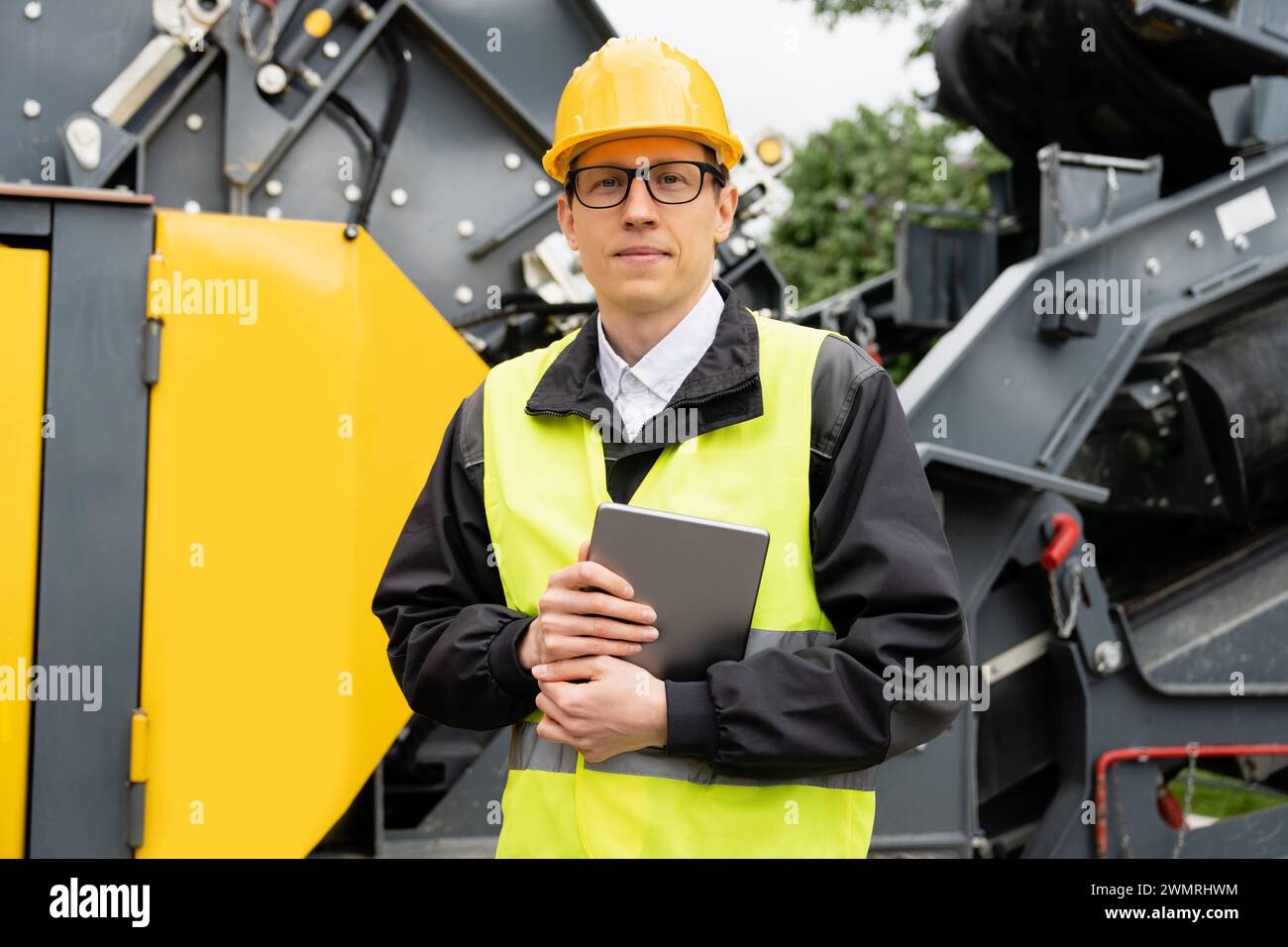 Concevoir avec une tablette numérique à côté de la machine de construction routière. Banque D'Images