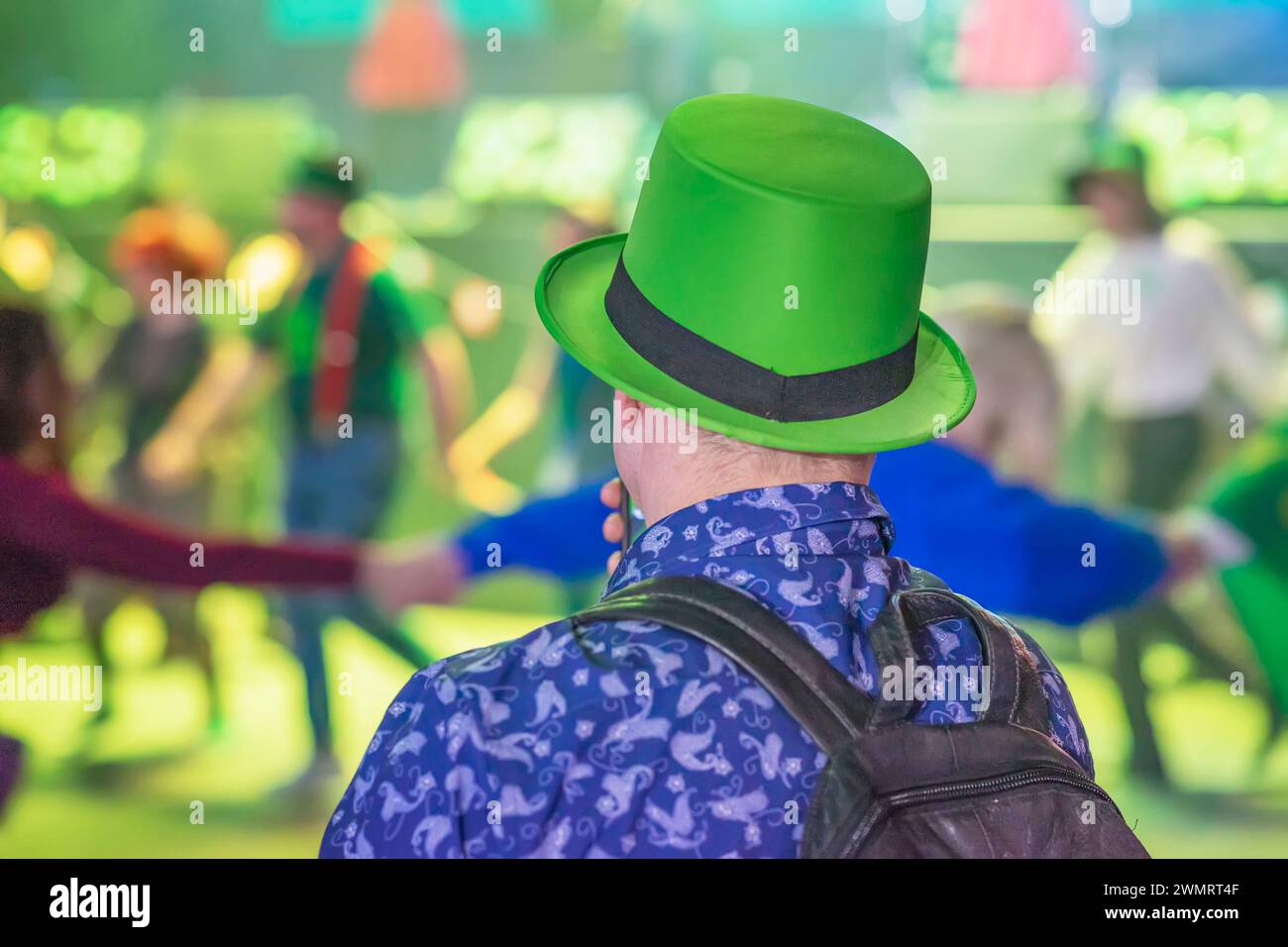Vue arrière de l'homme en chapeau vert sur fond flou de personnes s'amusant et dansant. Prog Célébration de la fête de Patrick Banque D'Images