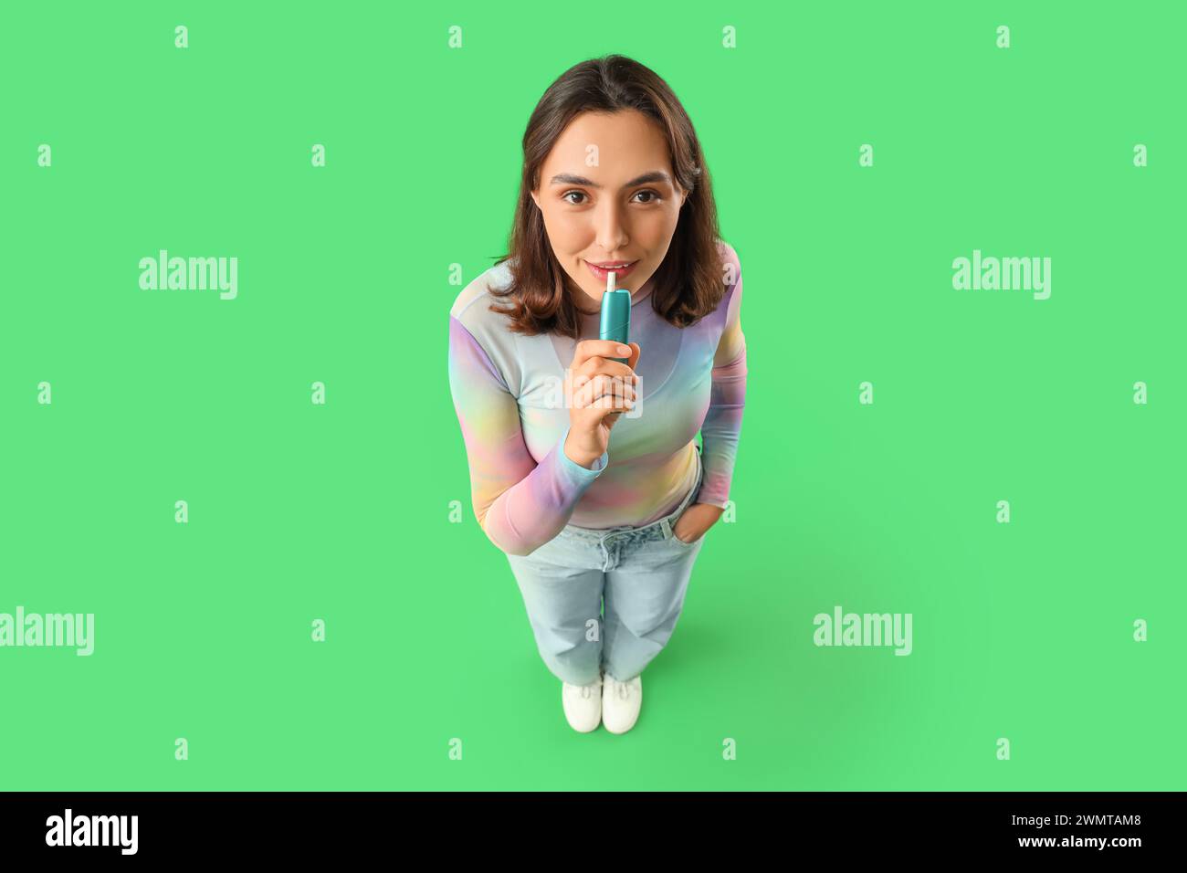 Jeune femme fumant cigare électronique sur fond vert Banque D'Images