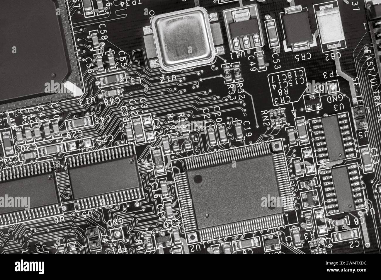 gros plan sur la carte de circuit imprimé avec des résistances, des condensateurs, des micropuces et des composants électroniques. b/w. Banque D'Images