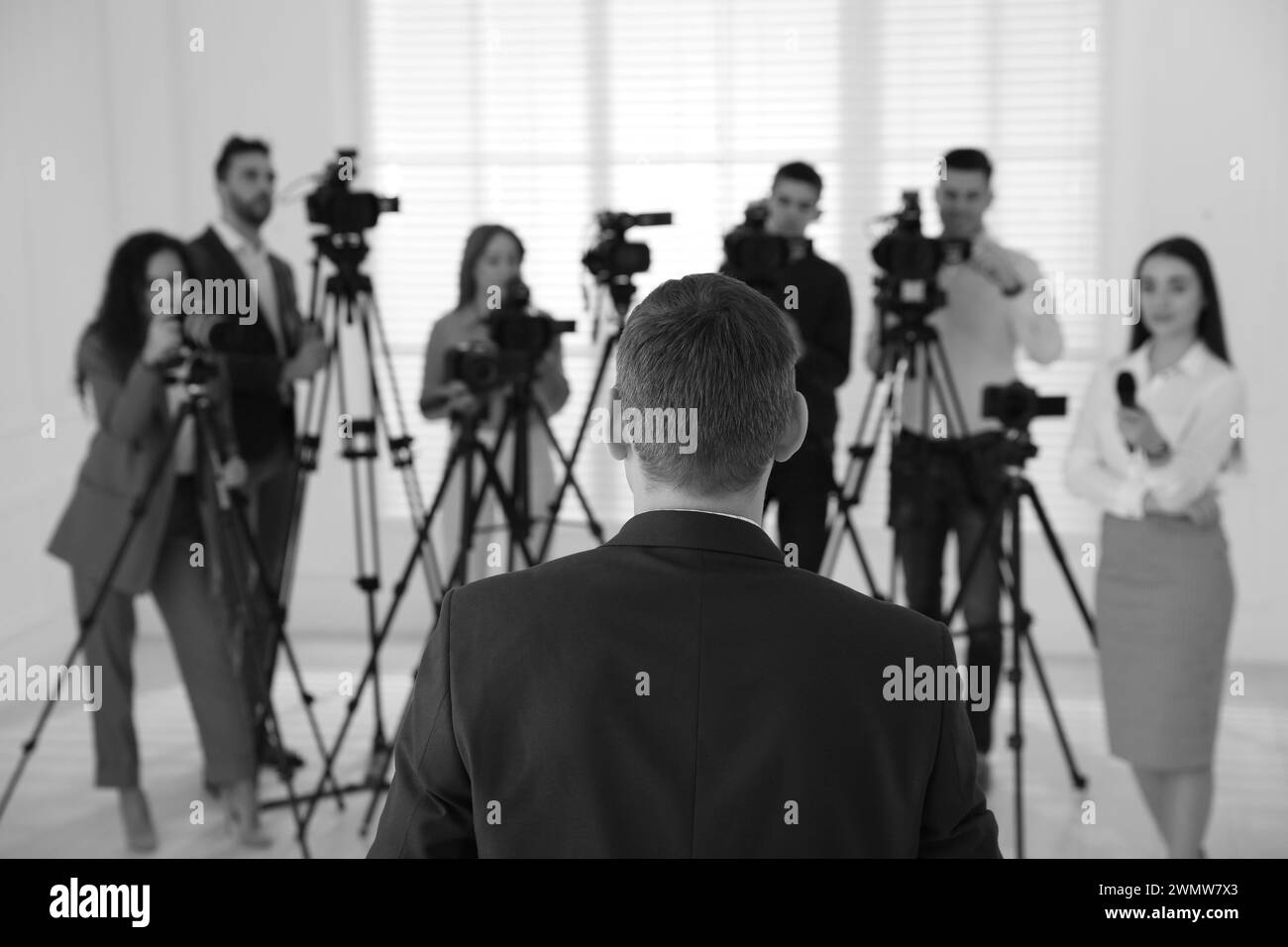 Homme d'affaires donnant une interview aux journalistes à l'intérieur, vue arrière. Effet noir et blanc Banque D'Images