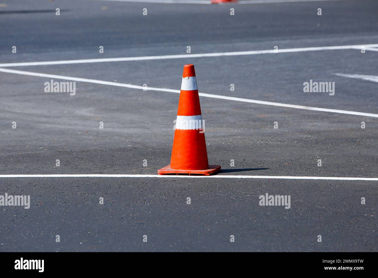 Un cône de circulation orange sur la route. Le cône se tient au milieu de la route, avertissant du danger. Le cône est en plastique et a un sh trapézoïdal Banque D'Images