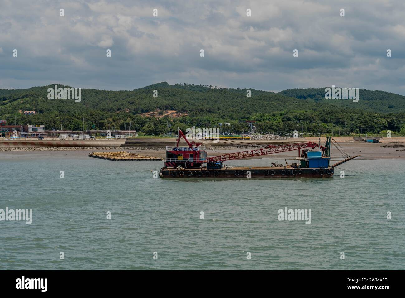 Barge avec grue rouge dans le port au port de Hongwon avec plage en arrière-plan en Corée du Sud Banque D'Images