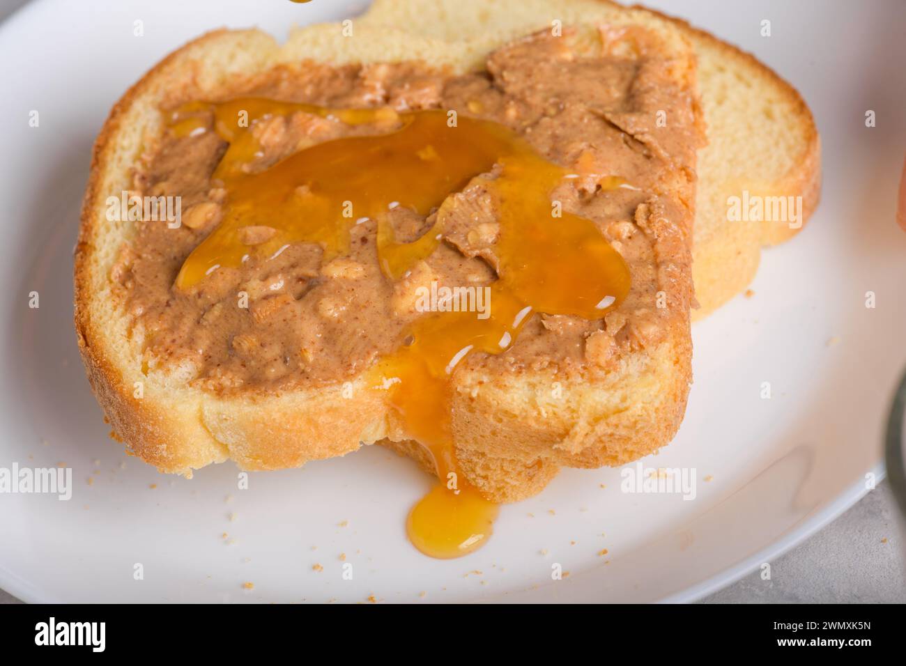 Sandwich avec miel et beurre d'arachide étalant sur un morceau de pain blanc toast, gros plan. Snack typique, style de vie alimentaire, vie domestique, américain b Banque D'Images