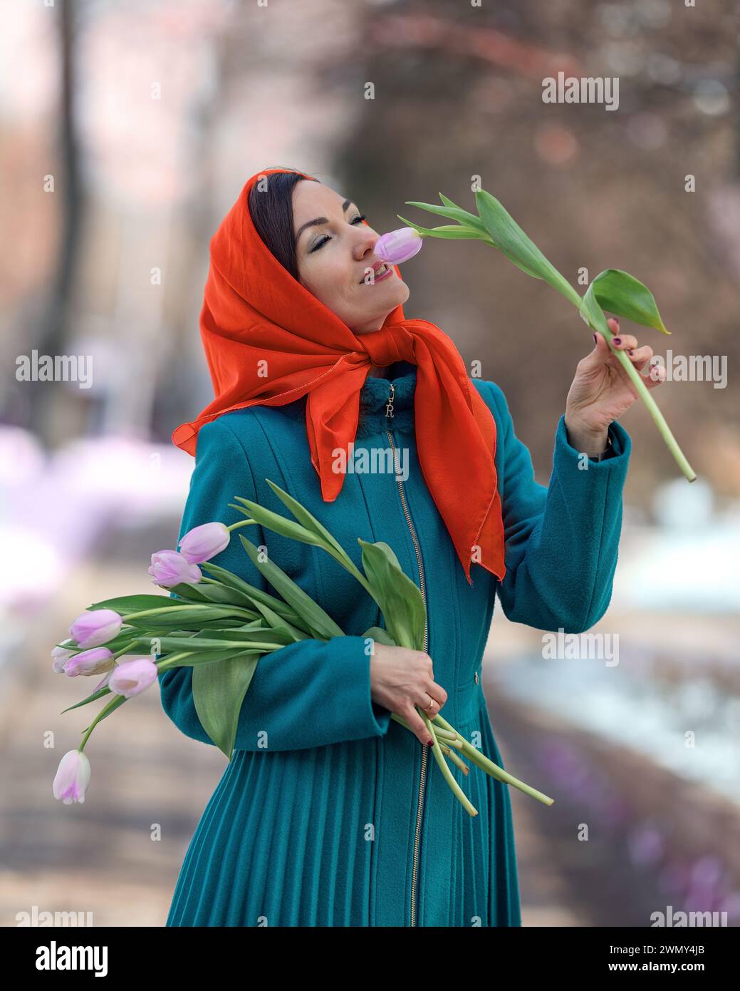 Belle femme avec bouquet de fleurs de tulipes de printemps à la rue de la ville. Portrait heureux de fille souriant et tenant des fleurs de tulipe roses à l'extérieur le 8 mars Banque D'Images