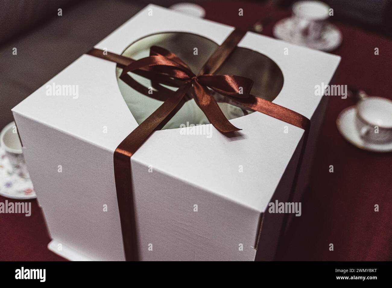 Gâteau d'anniversaire coloré avec des bougies allumées et des cadeaux emballés dans une grande boîte sur une table joliment décorée, créant une atmosphère joyeuse et festive Banque D'Images