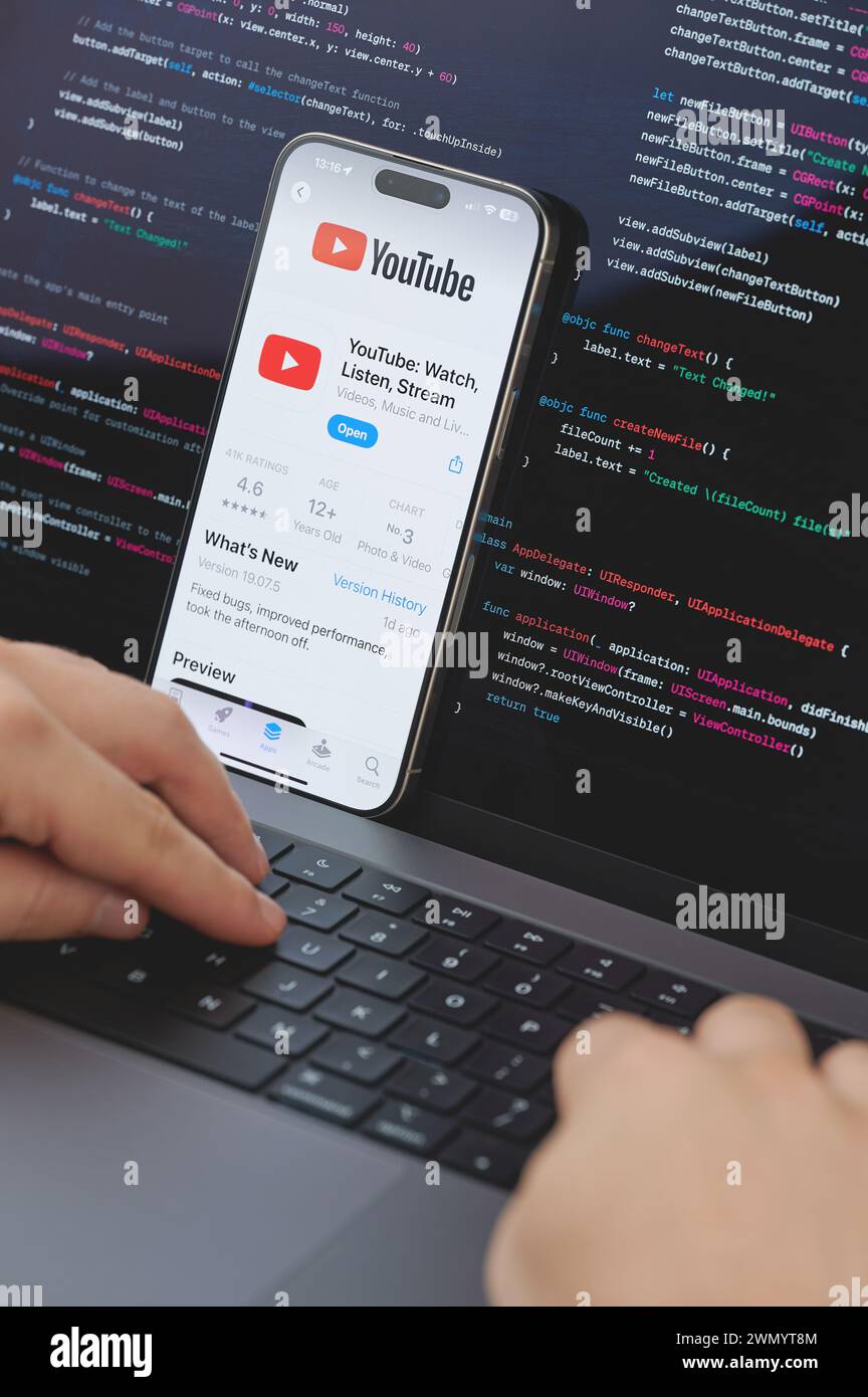 New York, USA - 23 février 2024 : Code pour la nouvelle application Youtube dans l'écran d'ordinateur portable avec les mains sur le clavier Banque D'Images