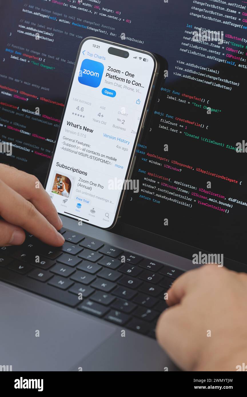 New York, États-Unis - 23 février 2024 : Code pour la nouvelle application Zoom sur l'écran d'ordinateur portable avec les mains sur le clavier Banque D'Images