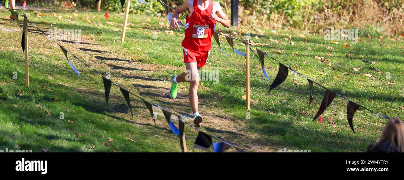 Coureur de cross-country de lycée courant sur un chemin descendant lors d'une course de cross-country au Bowdoin Park à Wappingersfalls New York. Banque D'Images