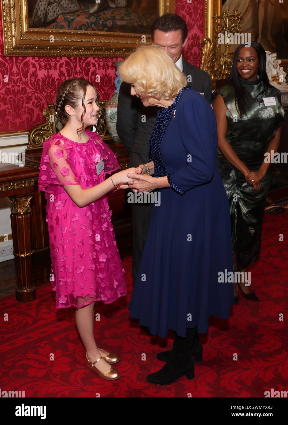 La reine Camilla s'entretient avec Alisha Weir lors d'une réception au Buckingham Palace à Londres avec des finalistes, des juges et des lecteurs célèbres, pour célébrer la finale du concours d'écriture créative de la BBC, 500 Words. Date de la photo : mercredi 28 février 2024. Banque D'Images