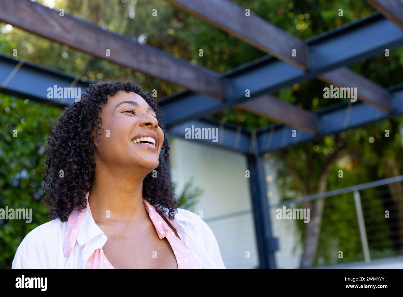 Jeune femme biraciale sourit brillamment, regardant vers le haut à l'extérieur à la maison avec un espace de copie Banque D'Images