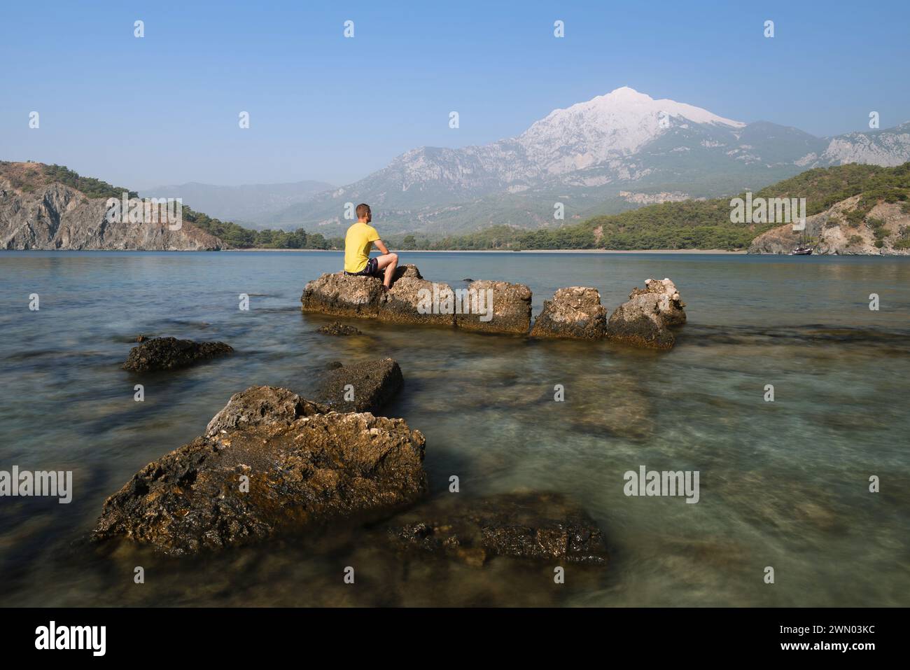 De la baie au rivage de la mer. Paysage d'été. Touriste assis sur un rocher et regardant les montagnes. Turquie Baie de Phaselis, Mont Tahtali Banque D'Images