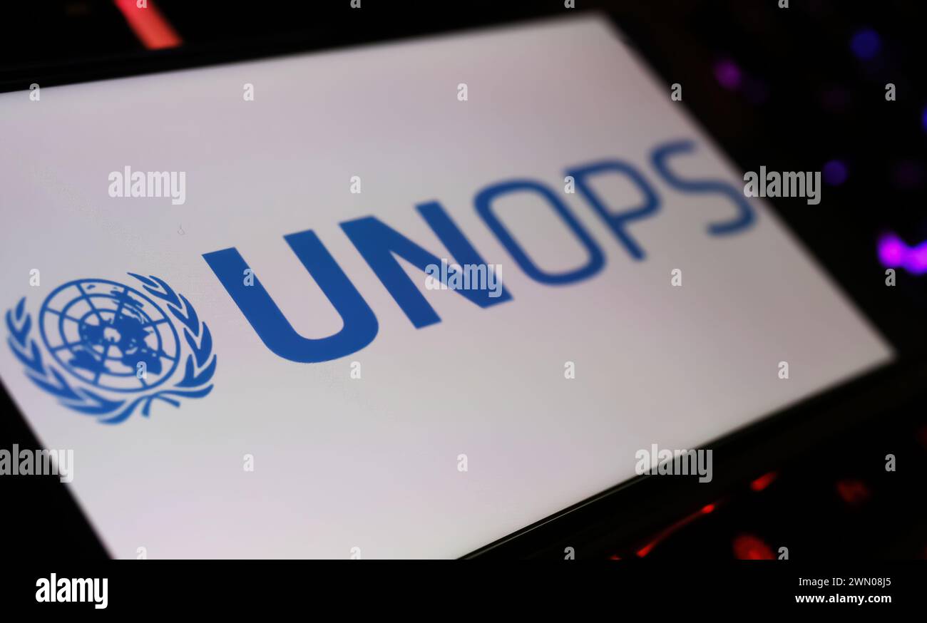 Viersen, Allemagne - 9 janvier. 2024 : écran de smartphone avec lettrage logo de l'agence des Nations unies UNOPS sur le clavier de l'ordinateur Banque D'Images