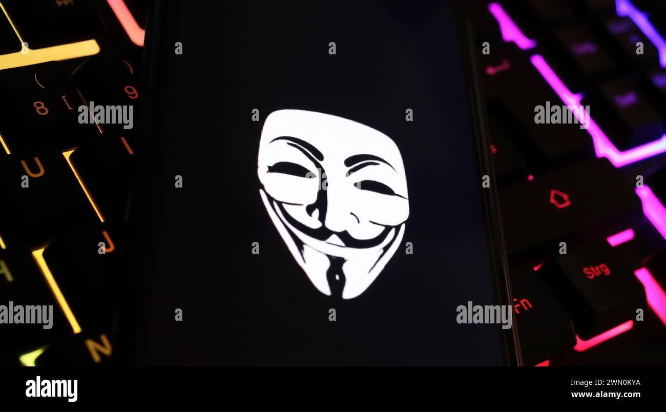 Viersen, Allemagne - 9 janvier. 2024 : écran de smartphone avec symbole de masque anonyme sur le clavier de l'ordinateur comme cyberattaque et concept de piratage Banque D'Images