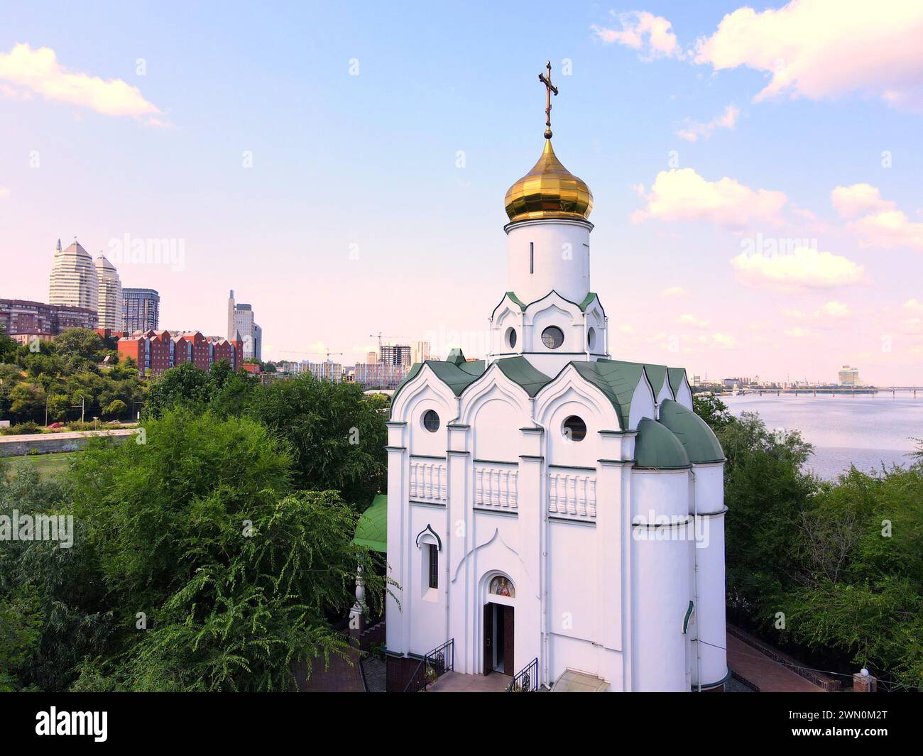 Belle église orthodoxe chrétienne blanche près de la rivière pour Pâques. Bâtiments et gratte-ciel dans la ville de Dnepr Ukraine. Paysage urbain ukrainien de Pâques Banque D'Images