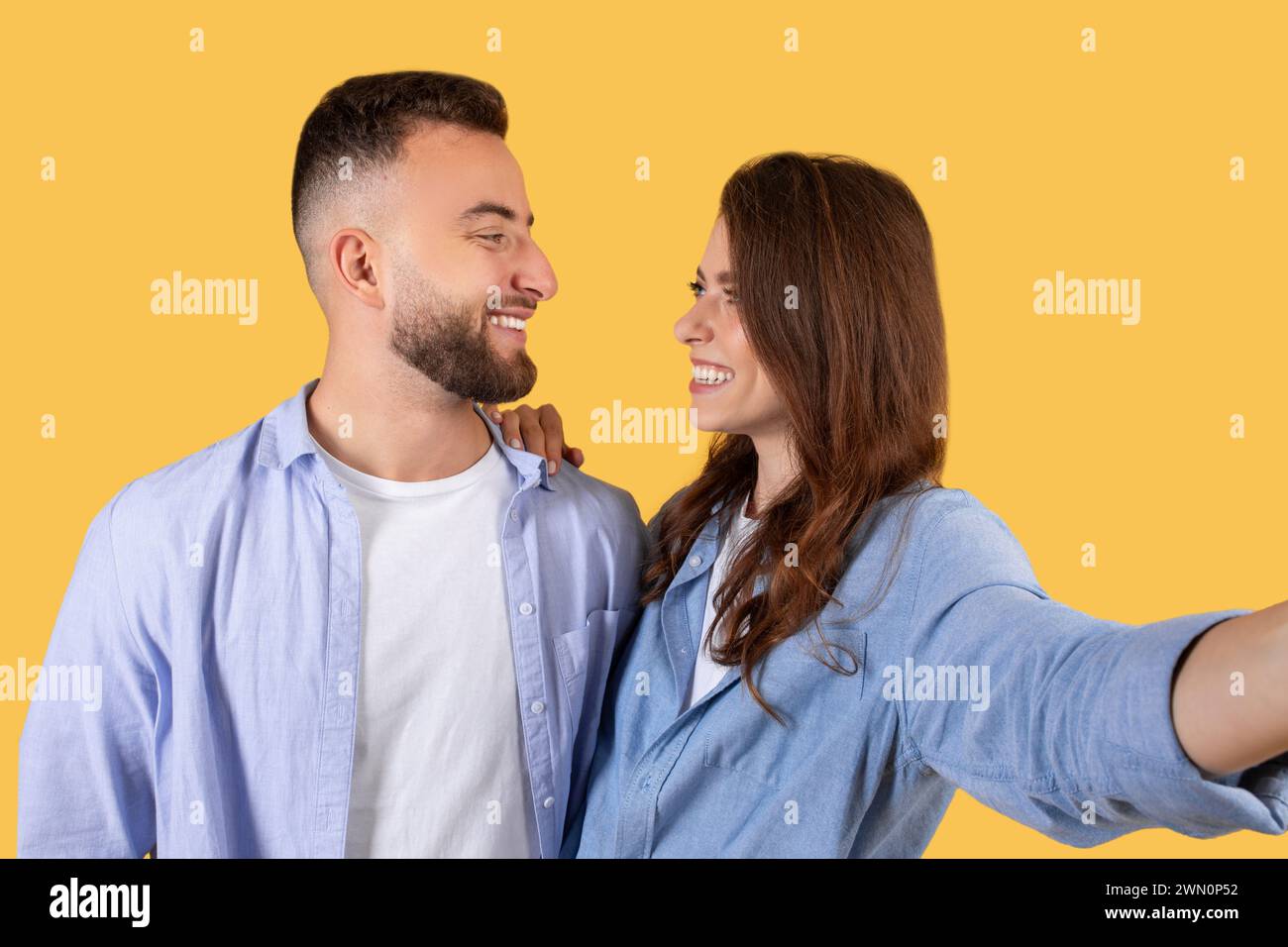 Jeune couple joyeux prenant selfie, se regardant et souriant Banque D'Images
