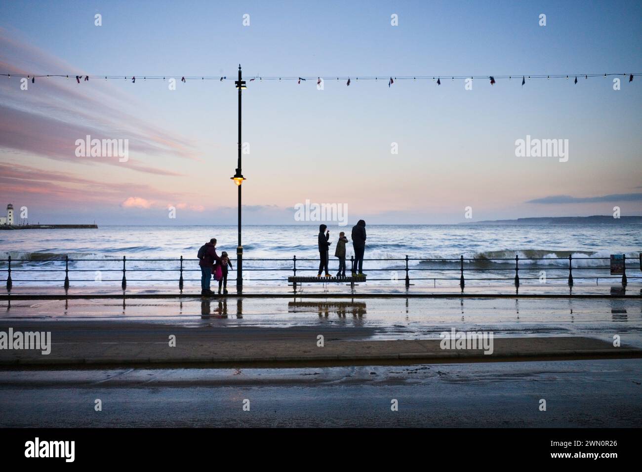 Les gens sur le front de mer à Scarborough debout sur des sièges pour éviter de se mouiller par les marées hautes Banque D'Images