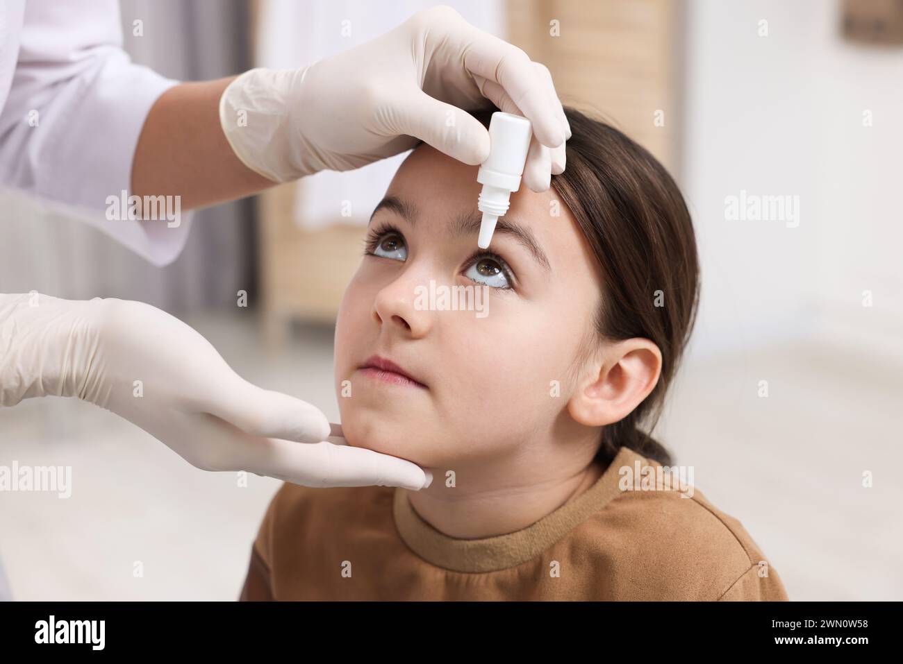 Docteur appliquant des gouttes médicales dans l'oeil de la fille à l'intérieur Banque D'Images