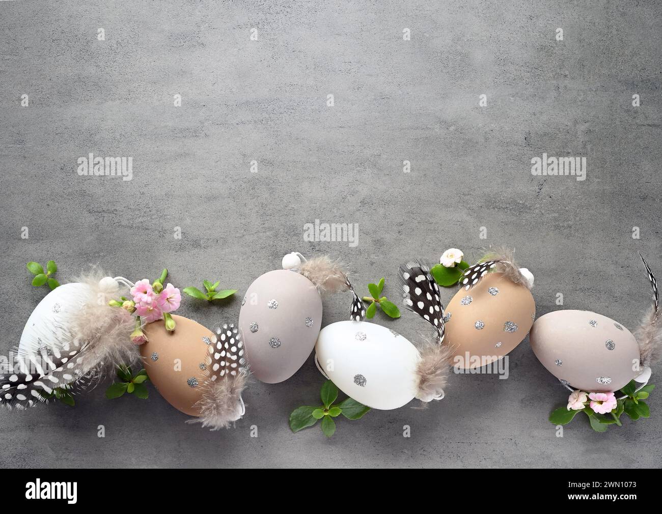 Collection d'oeufs de couleurs élégantes avec des fleurs pour la célébration de Pâques sur fond gris. Concept de vacances. Banque D'Images