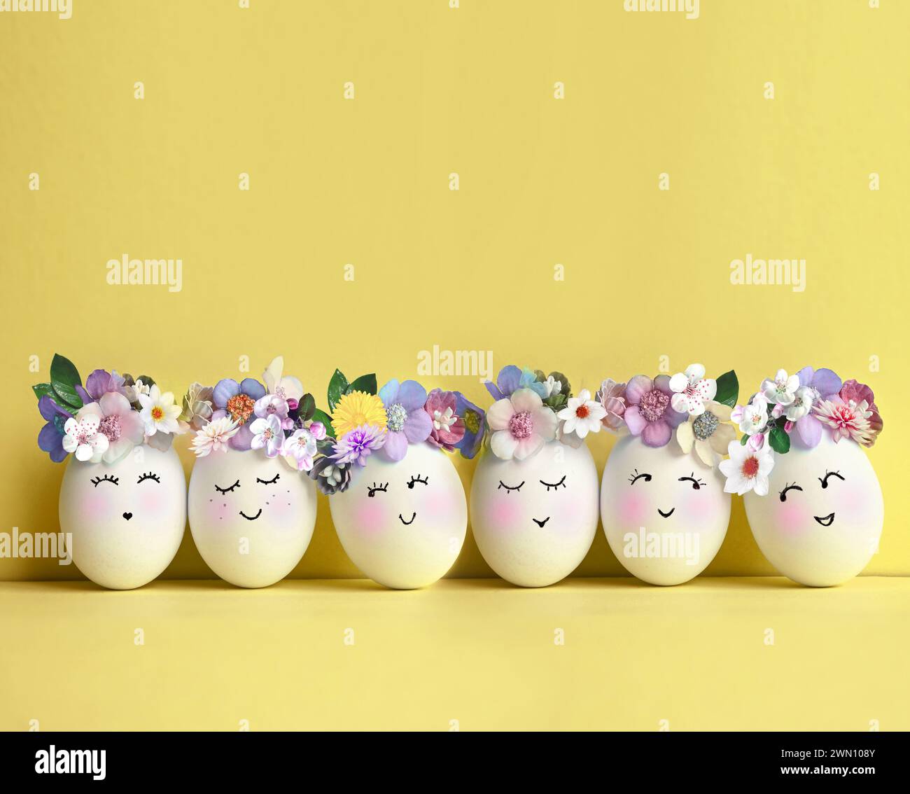 Collection d'oeufs de couleurs élégantes avec des fleurs pour la célébration de Pâques sur fond jaune. Concept de vacances. Banque D'Images