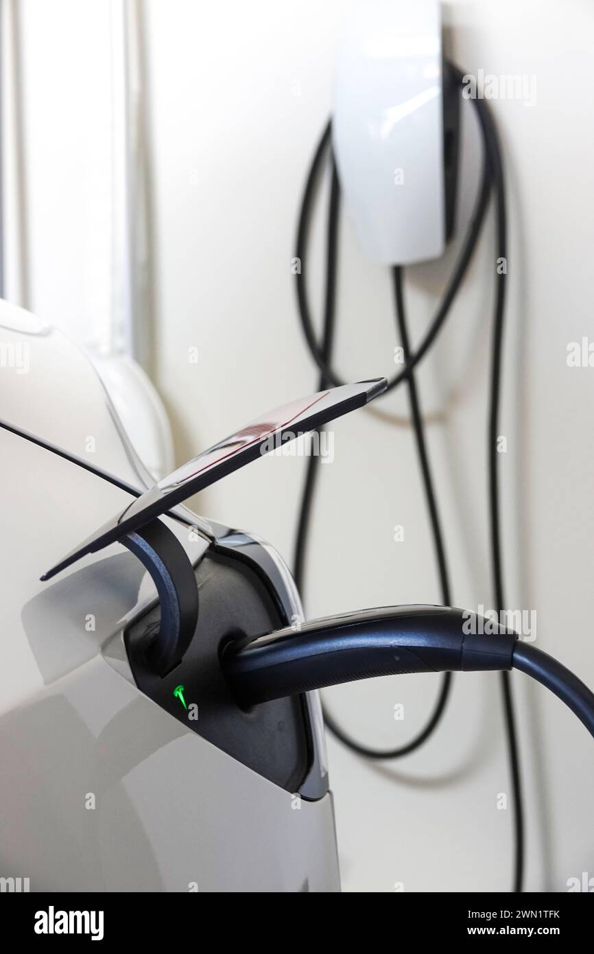 Tesla EV charge dans un garage à domicile branché à un chargeur mural Banque D'Images