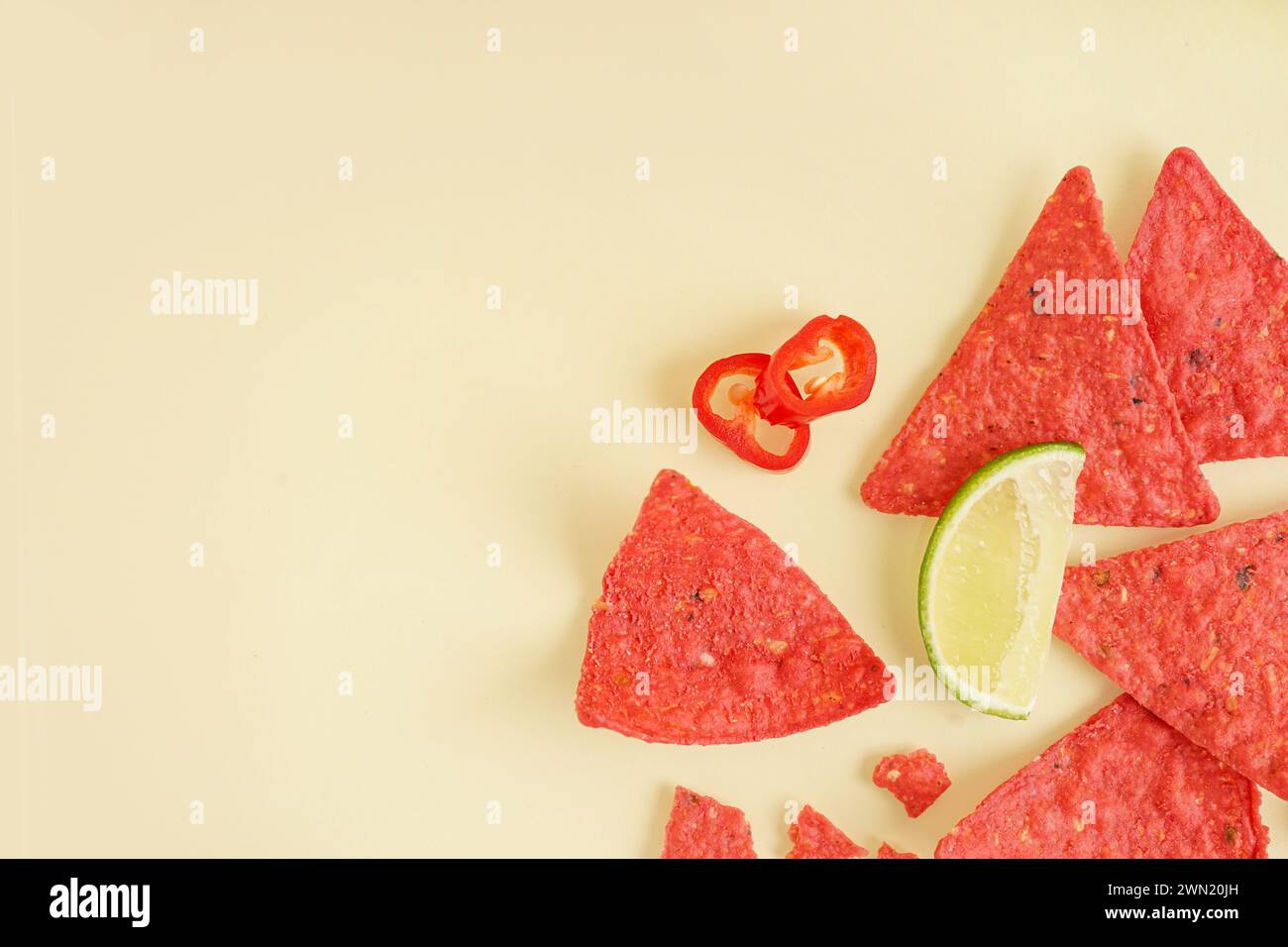 Nachos rouges avec citron vert et piment sur fond jaune Banque D'Images