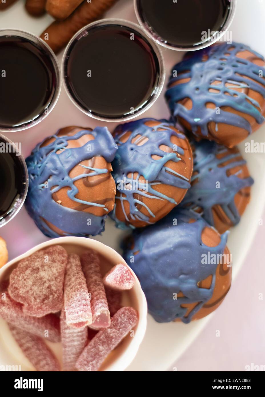 Un plateau de fête pour une fête d'anniversaire d'enfant avec des aliments sucrés colorés comprenant des sucettes, des bonbons, de la gelée et des biscuits enrobés de chocolat violet. Banque D'Images