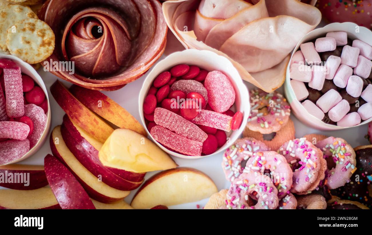 Un plateau de fête pour une fête d'anniversaire d'enfant avec des aliments colorés à la fois sucrés et salés comprenant des viandes froides, des fruits, des craquelins, des biscuits, des sucettes, bonbons. Banque D'Images