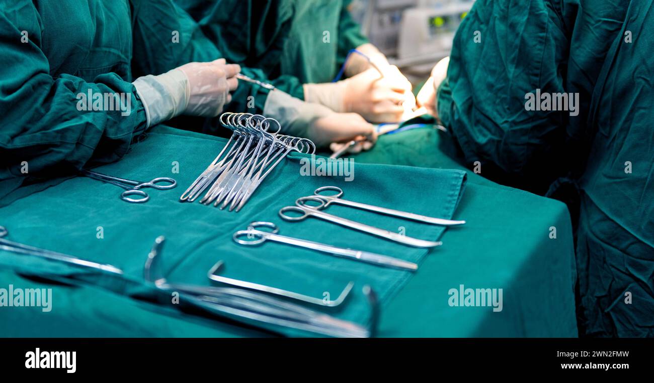 Les chirurgiens opèrent avec une infirmière préparant des instruments médicaux Banque D'Images