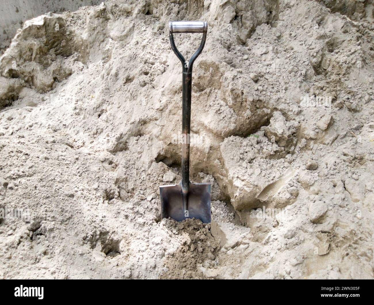 Une pelle coincée dans le sable sur un chantier de construction Banque D'Images