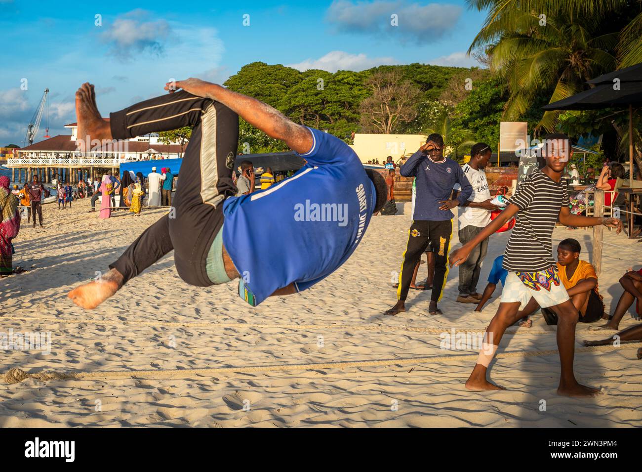 Un jeune homme effectue des acrobaties en fin d'après-midi sur la plage de Stone Town, Zanzibar, Tanzanie. Banque D'Images