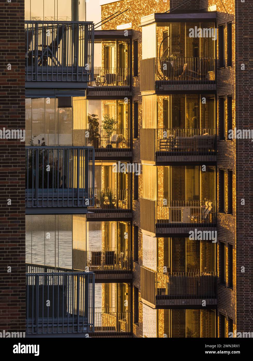 Le soleil couchant baigne les balcons modernes d'un immeuble résidentiel à Gothenburg, en Suède, dans une lueur chaude. Les balustrades en verre reflètent le coucher du soleil Banque D'Images