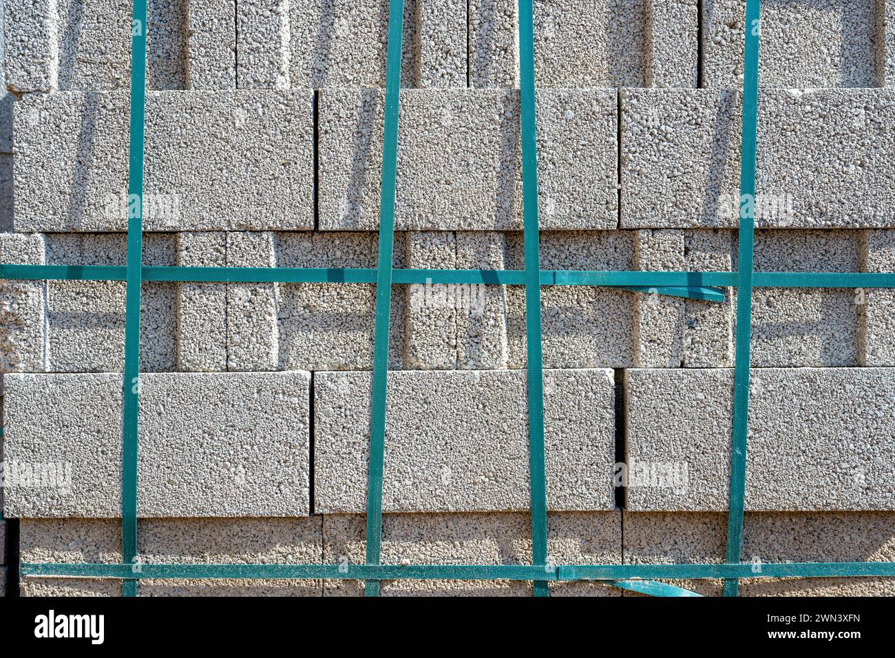 Bloc de cendre de ciment gris debout l'un sur l'autre et attaché avec une bande sur le chantier de construction Banque D'Images