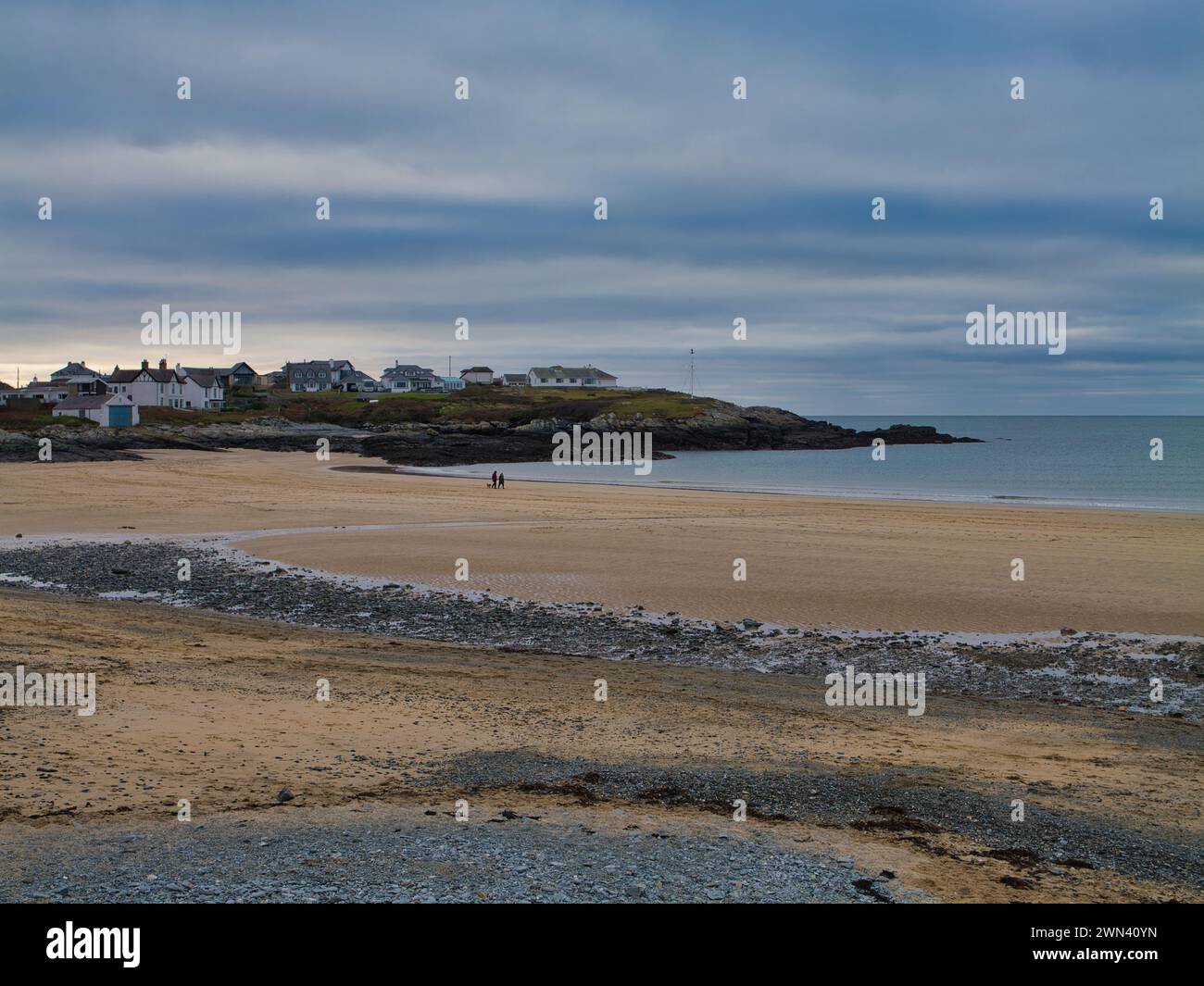 Trearddur Bay, Royaume-Uni - 11 janvier 2024 : un couple non identifié marche sur une plage de Traeth Trearddur - Trearddur autrement déserte en hiver Banque D'Images