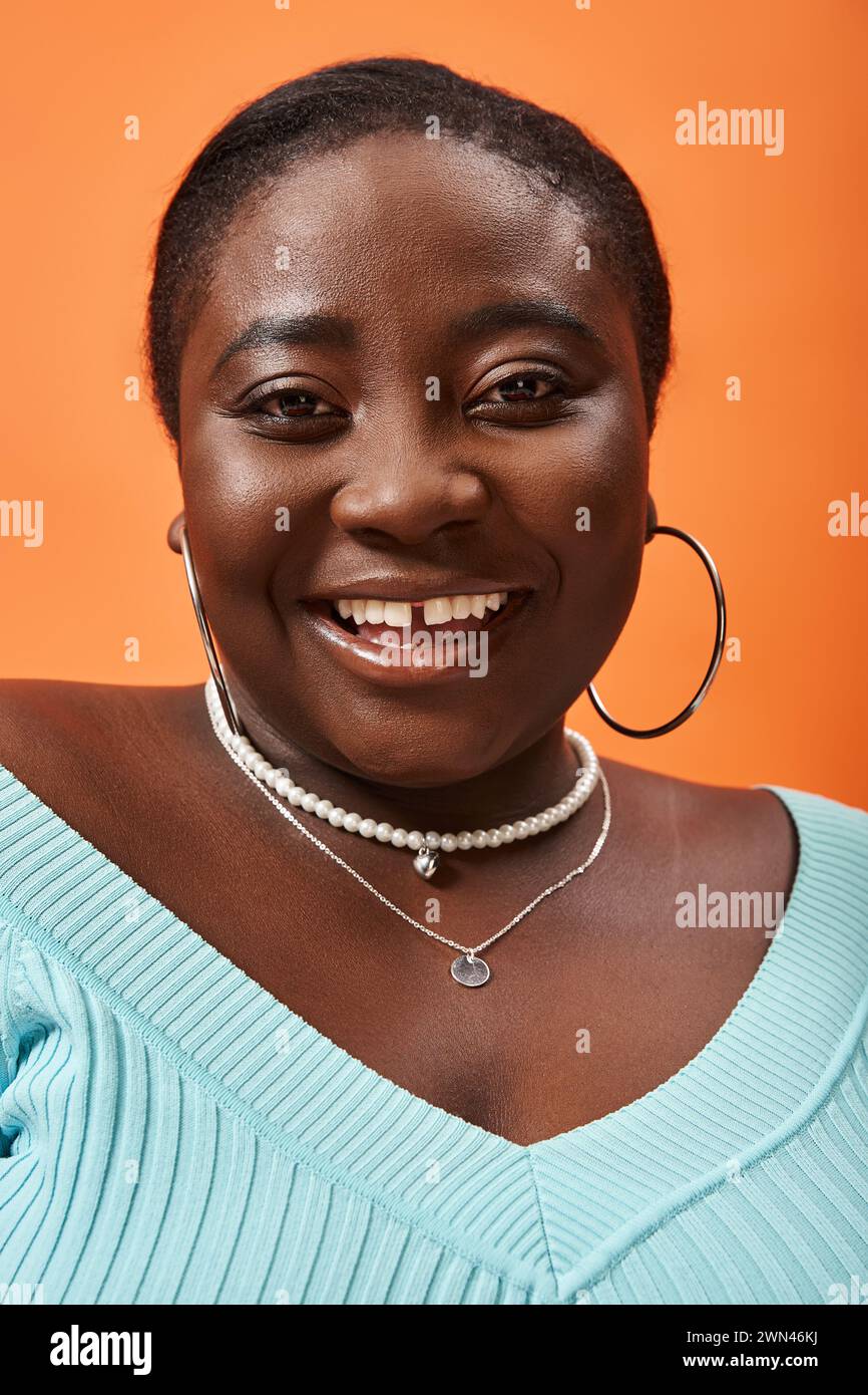 portrait de corps positif jeune femme afro-américaine en manches longues bleues sur fond orange Banque D'Images