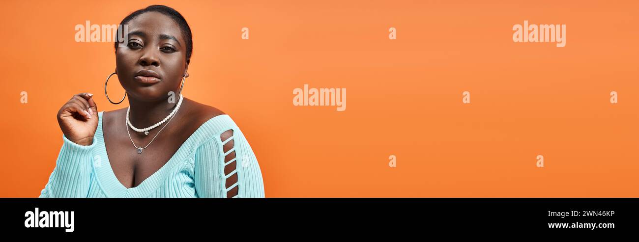 body positive afro-américaine femme en jupe à carreaux et manches longues bleues regardant la caméra, la bannière Banque D'Images
