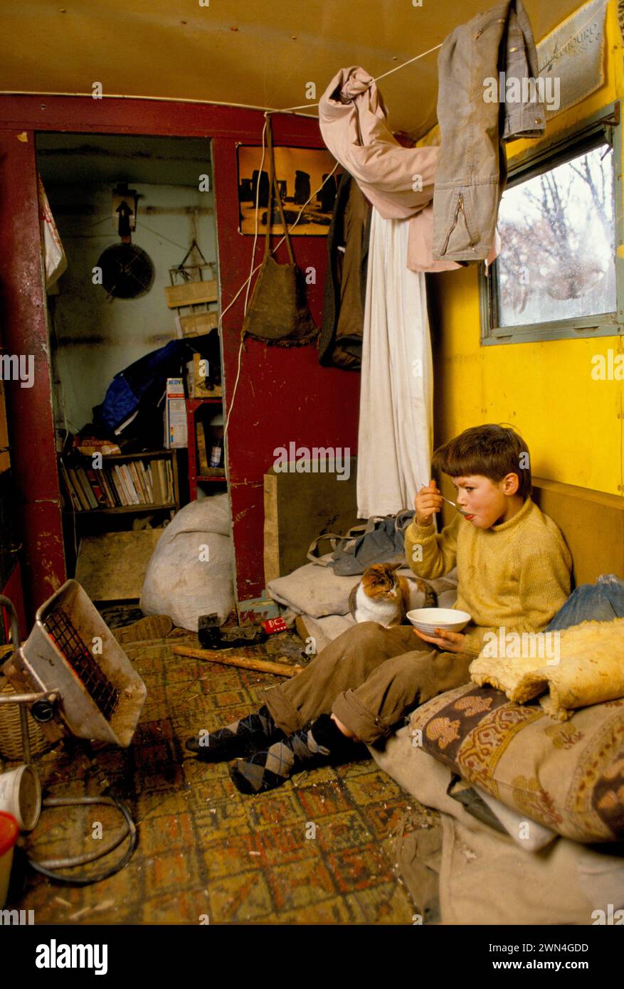 Living Off Grid 1980s UK. Enfant, jeune garçon dans le bureau de son père - un camping-car, il mange son petit déjeuner. Kevin Oubridge vivait avec sa famille dans la vallée de Tipi, une communauté hippie galloise qui abritait environ 120 spiritueux libres respectueux de l'environnement. Llandeilo, pays de Galles 1985 HOMER SYKES Banque D'Images