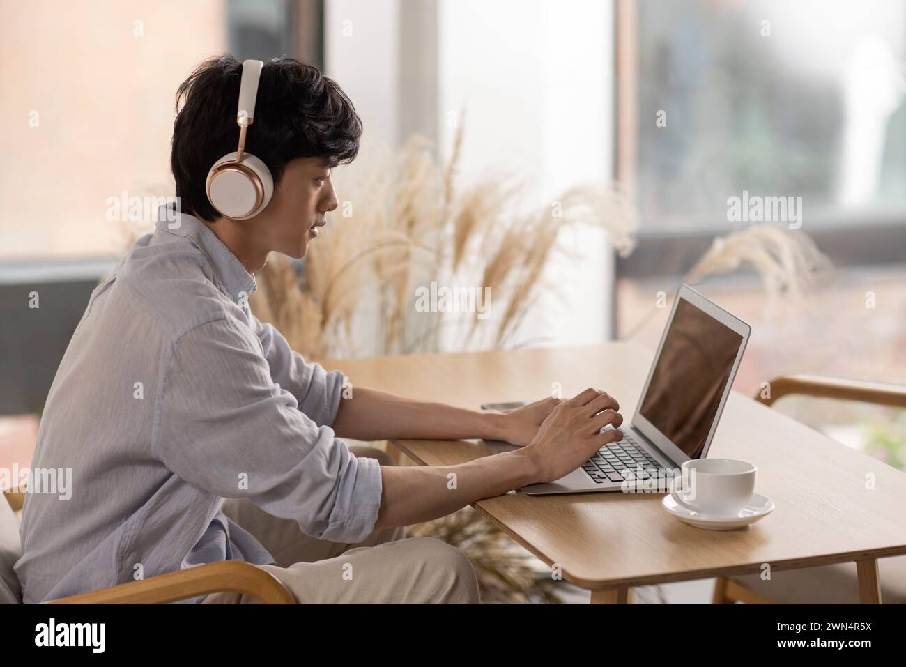Jeune homme utilisant un ordinateur portable dans un café Banque D'Images