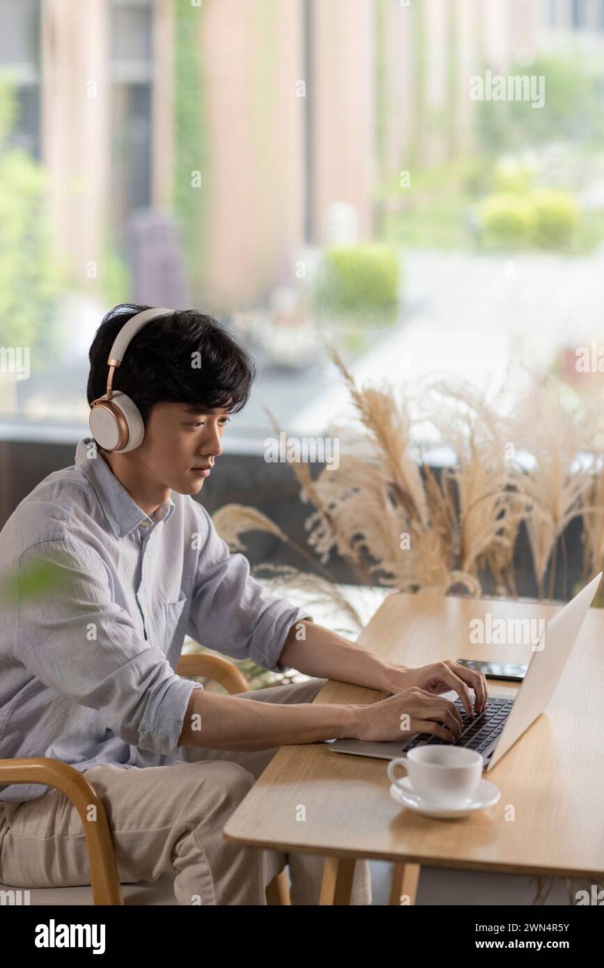 Jeune homme utilisant un ordinateur portable dans un café Banque D'Images