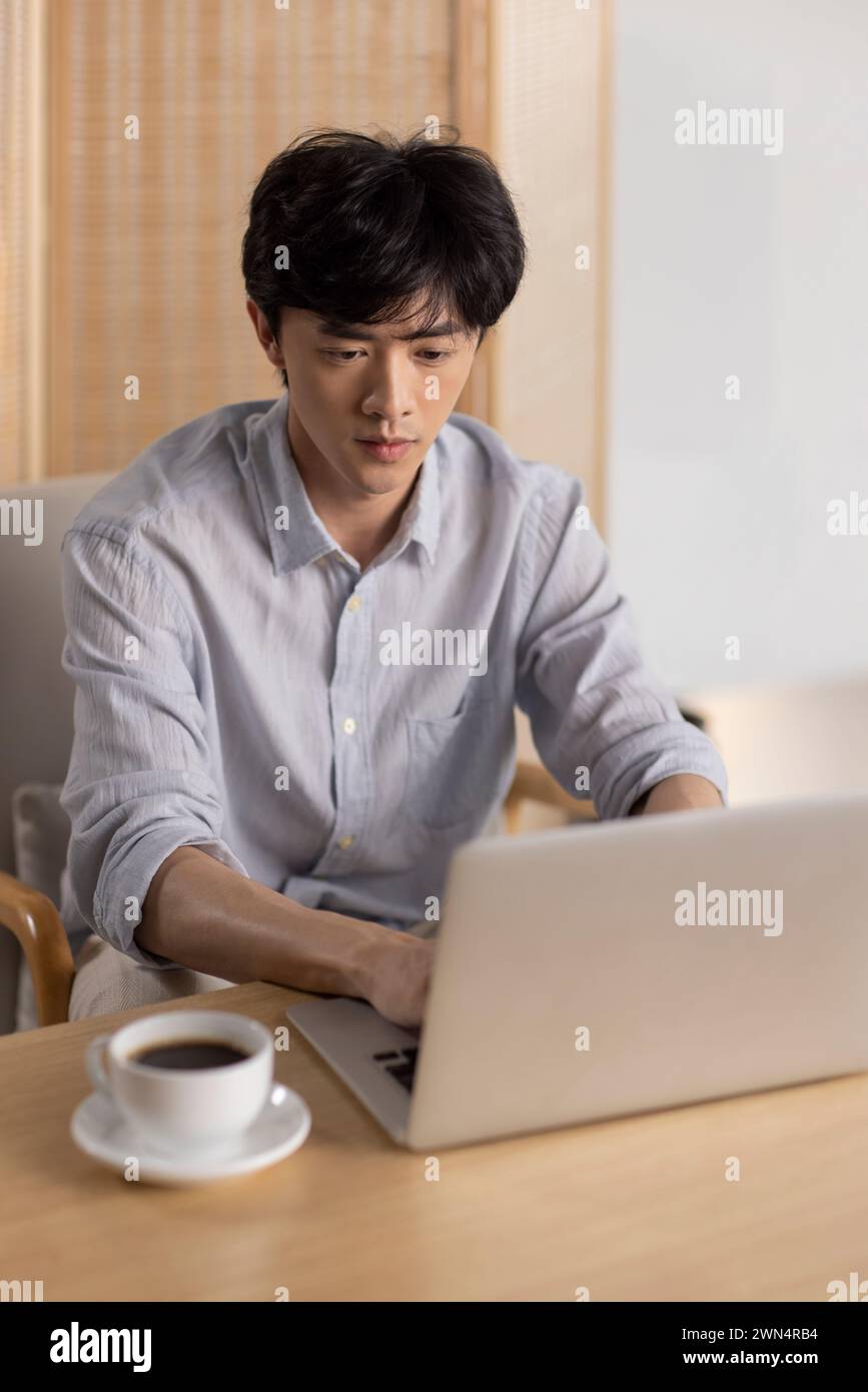 Jeune homme chinois utilisant un ordinateur portable dans un café Banque D'Images