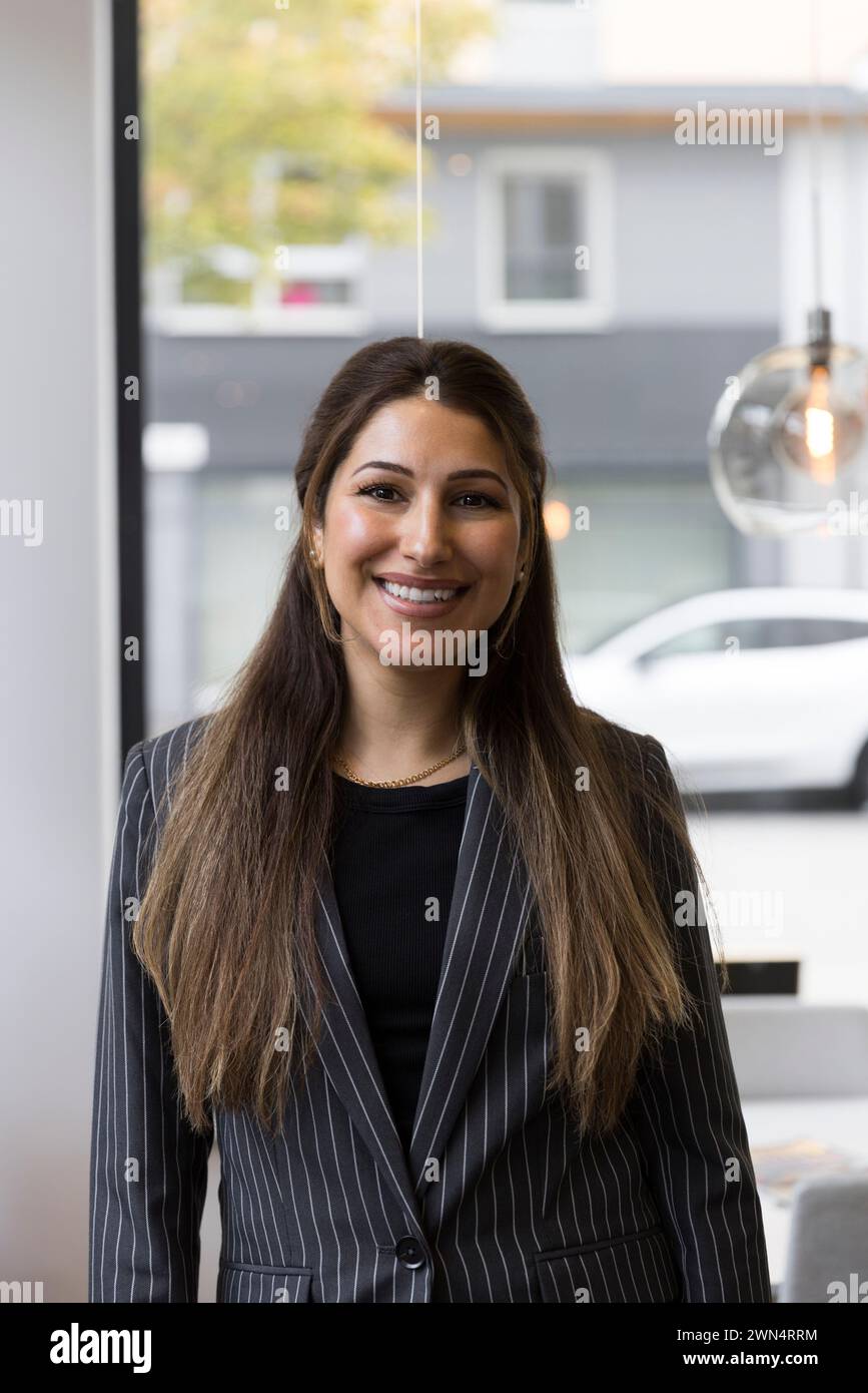 Portrait d'agent immobilier féminin souriant portant un blazer debout dans le bureau Banque D'Images