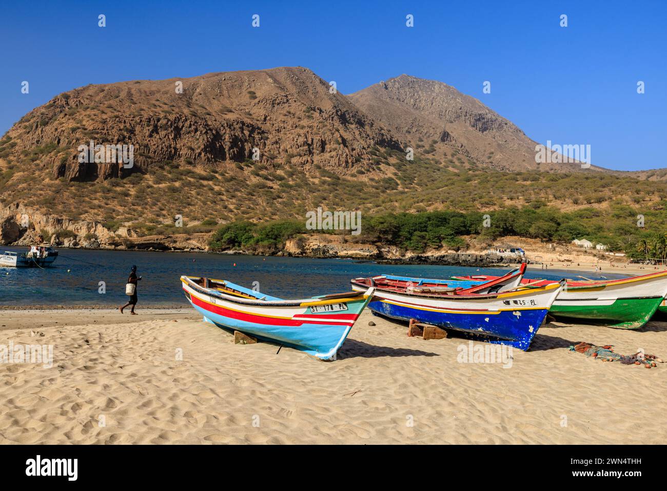 Belle plage de sable blanc avec des bateaux de pêche en bois coloré et baie calme et montagne rocheuse à Tarrafel Santiago île cabo verde Banque D'Images