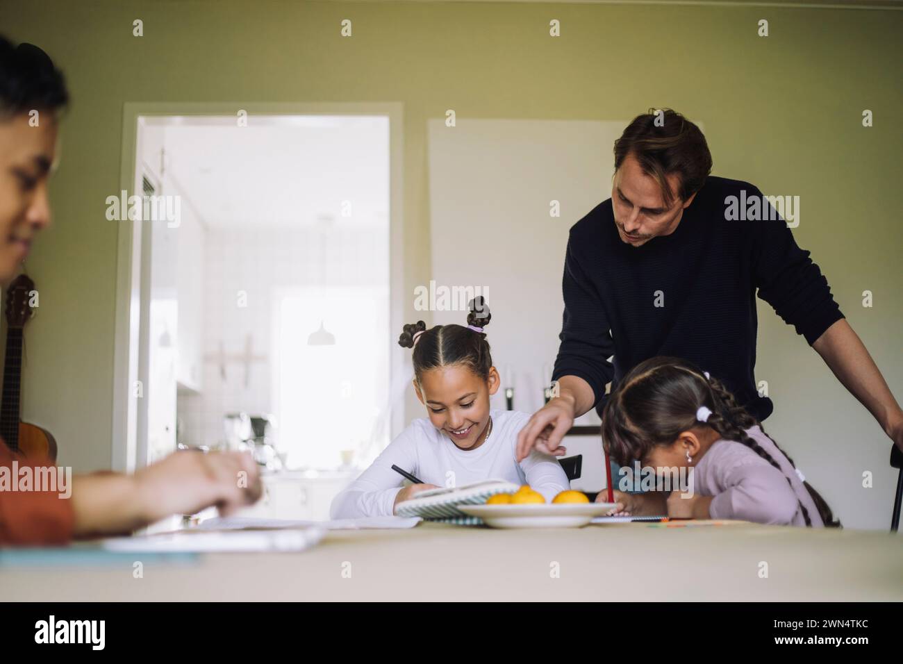 Père filles scolarisées à la maison assises à la table à manger Banque D'Images