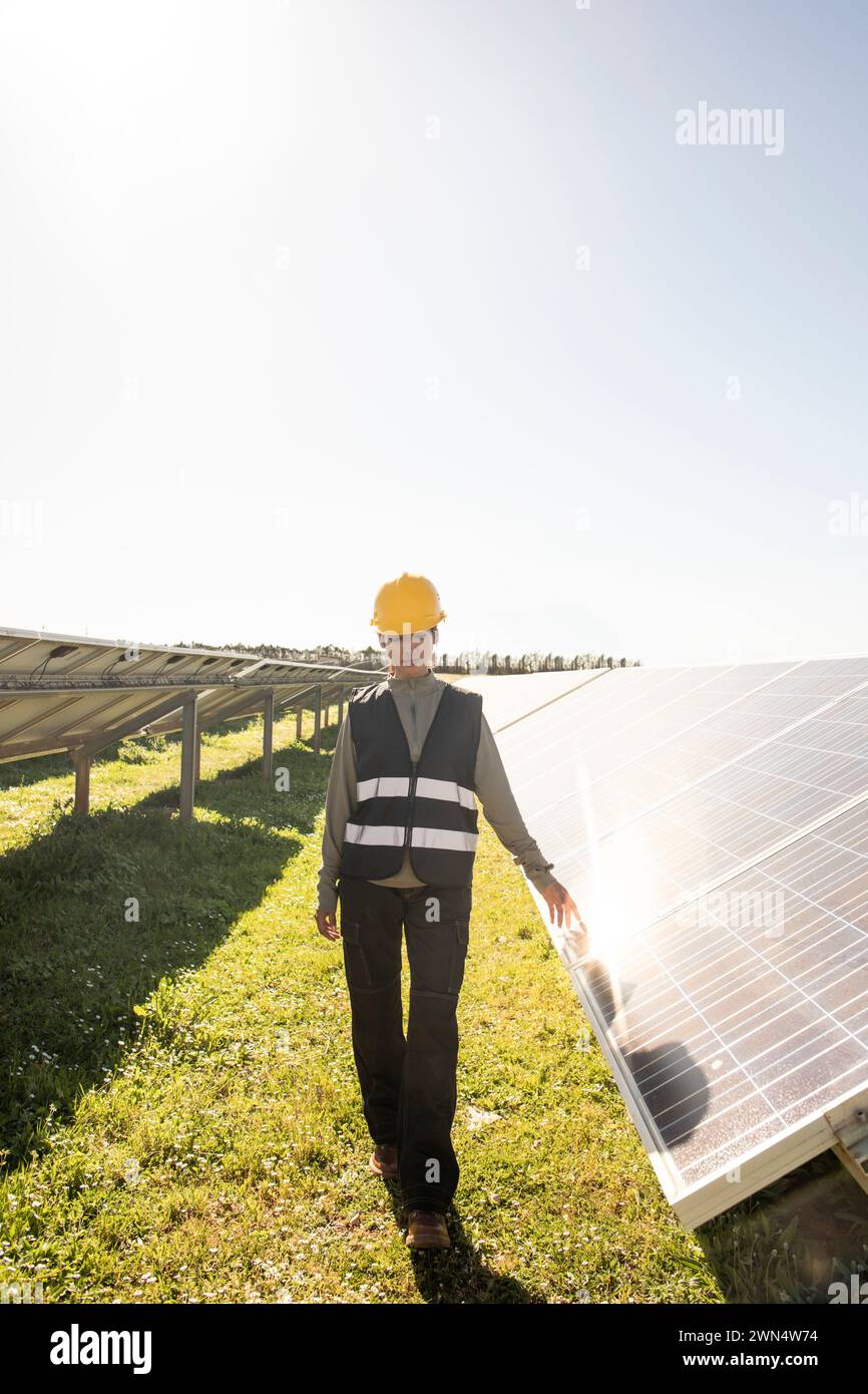 Femme ingénieur de maintenance marchant près des panneaux solaires à la centrale électrique Banque D'Images
