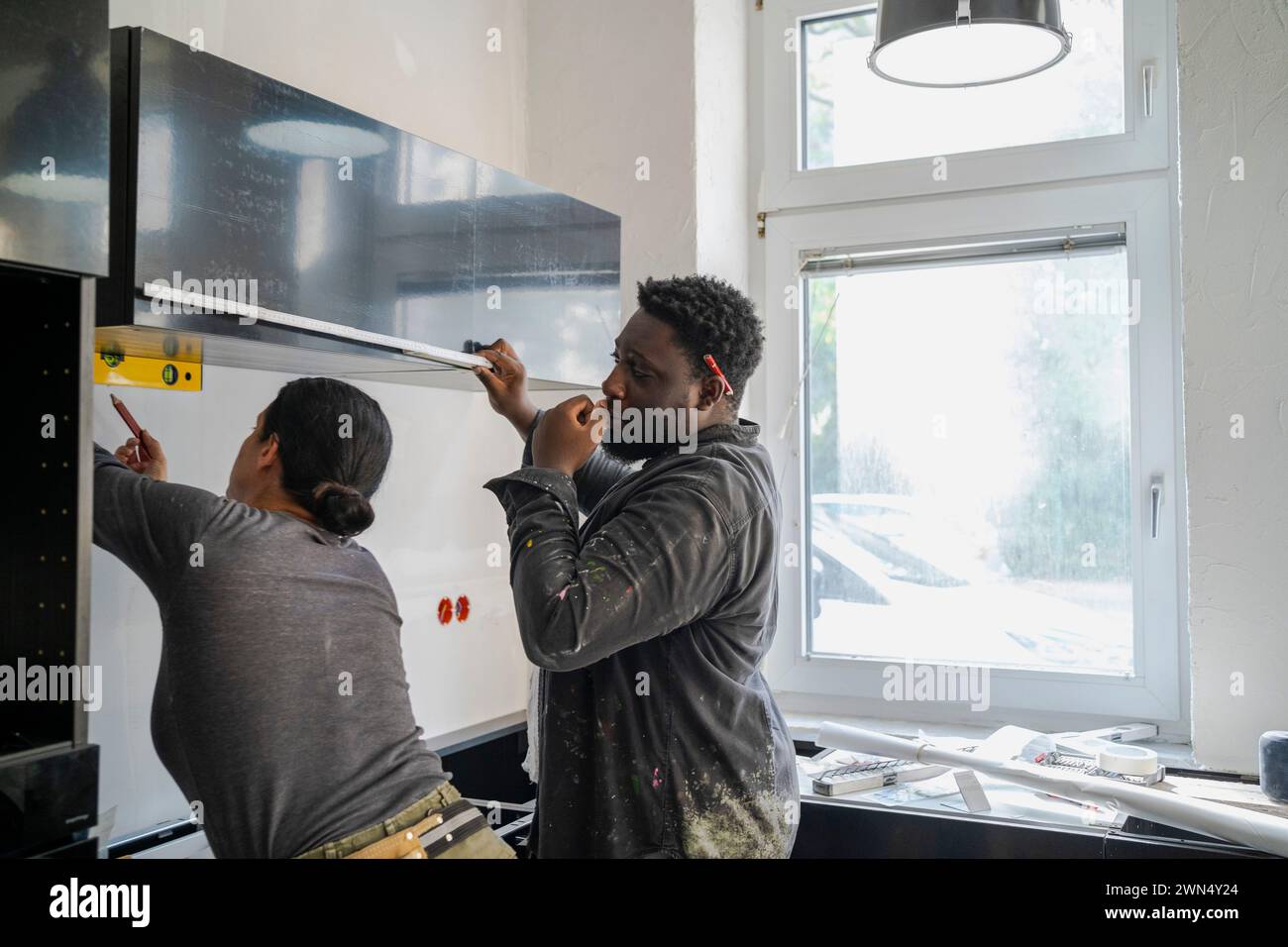 Divers menuisiers masculins et féminins travaillant ensemble dans la cuisine à l'appartement Banque D'Images