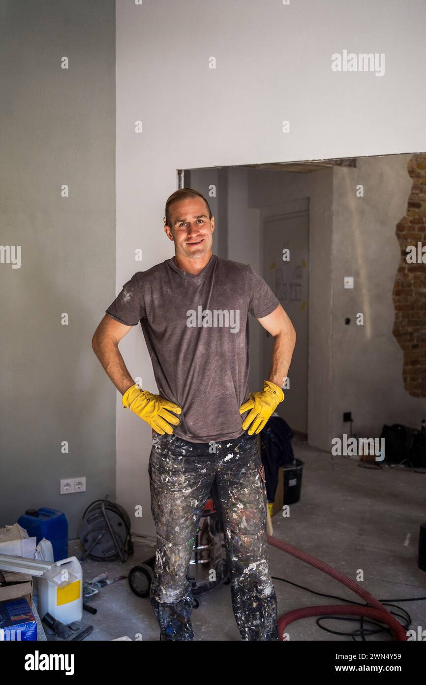 Portrait de charpentier masculin confiant debout avec les bras akimbo dans la chambre à la maison Banque D'Images