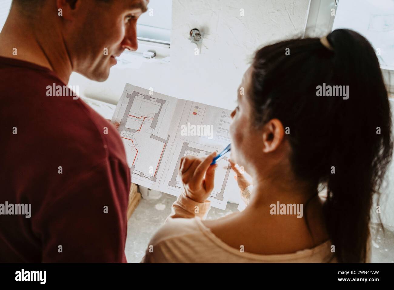 Vue en angle élevé du couple discutant sur le plan tout en rénovant la maison Banque D'Images